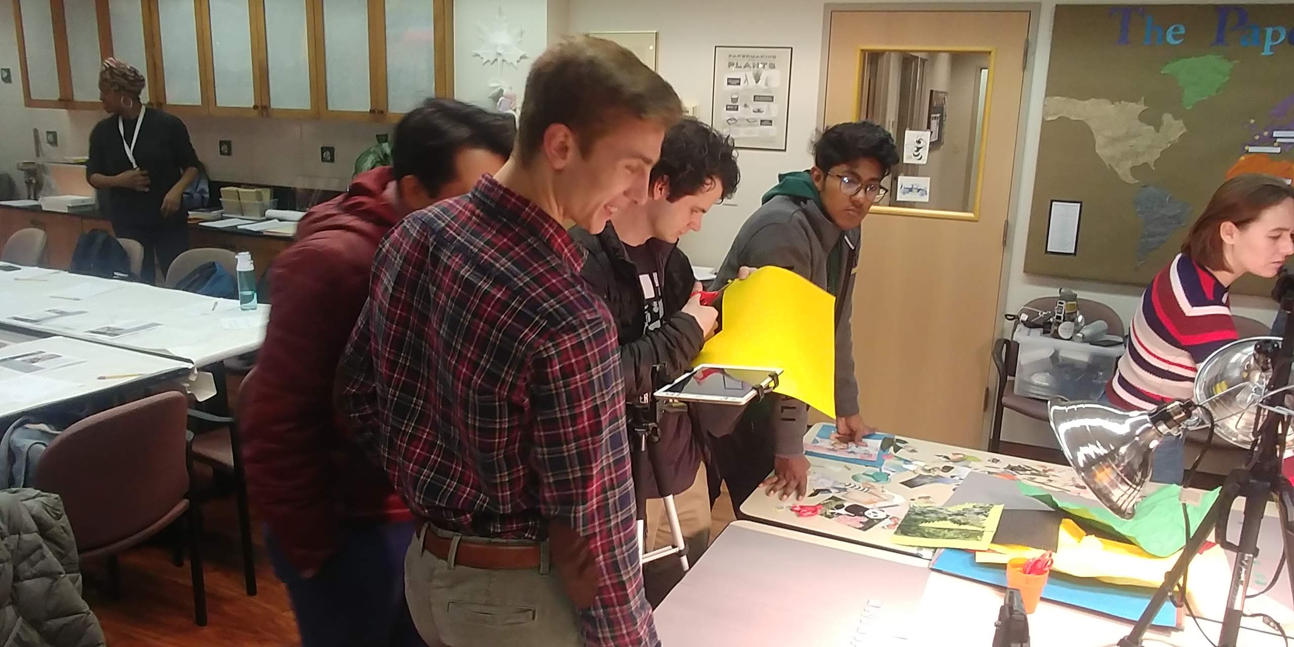 Photo of a stop motion workshop. Students working at a table with clamp lamps and collage background on the table.