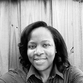 Black and white head shot of Artist, Casandra Brewton-Johnson, an African-American woman with straight hair to her shoulders smiling at the camera