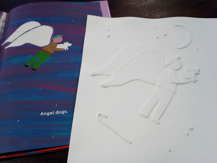 A full color children's book with an angel holding a dog sitting next to an all white embossed version of the same illustration created for blind and visually impaired readers